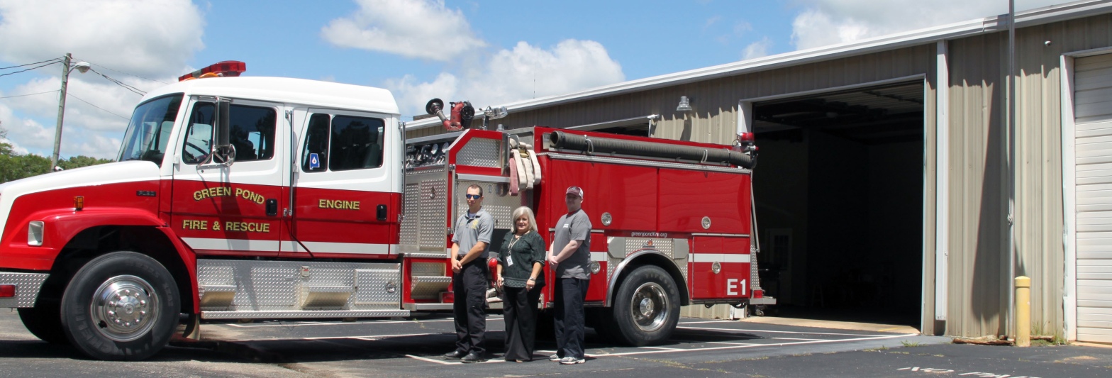 Dustin Rowe, Tammy Lovell, and Joseph Hall stand in front of a fire truck